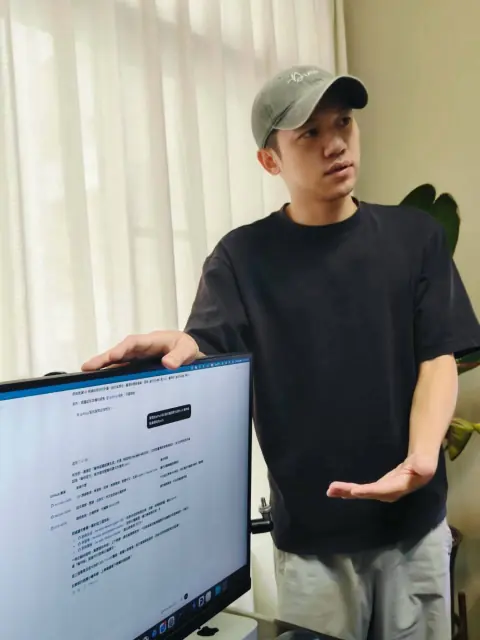 小刁站在螢幕旁邊，一手比著講解