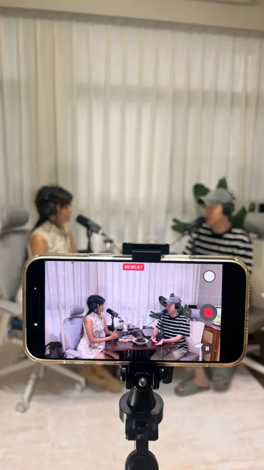 手機架在腳架上,錄下兩個人坐在桌邊對談