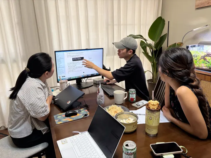 小刁指著螢幕講解,兩位夥伴坐在桌邊一起看